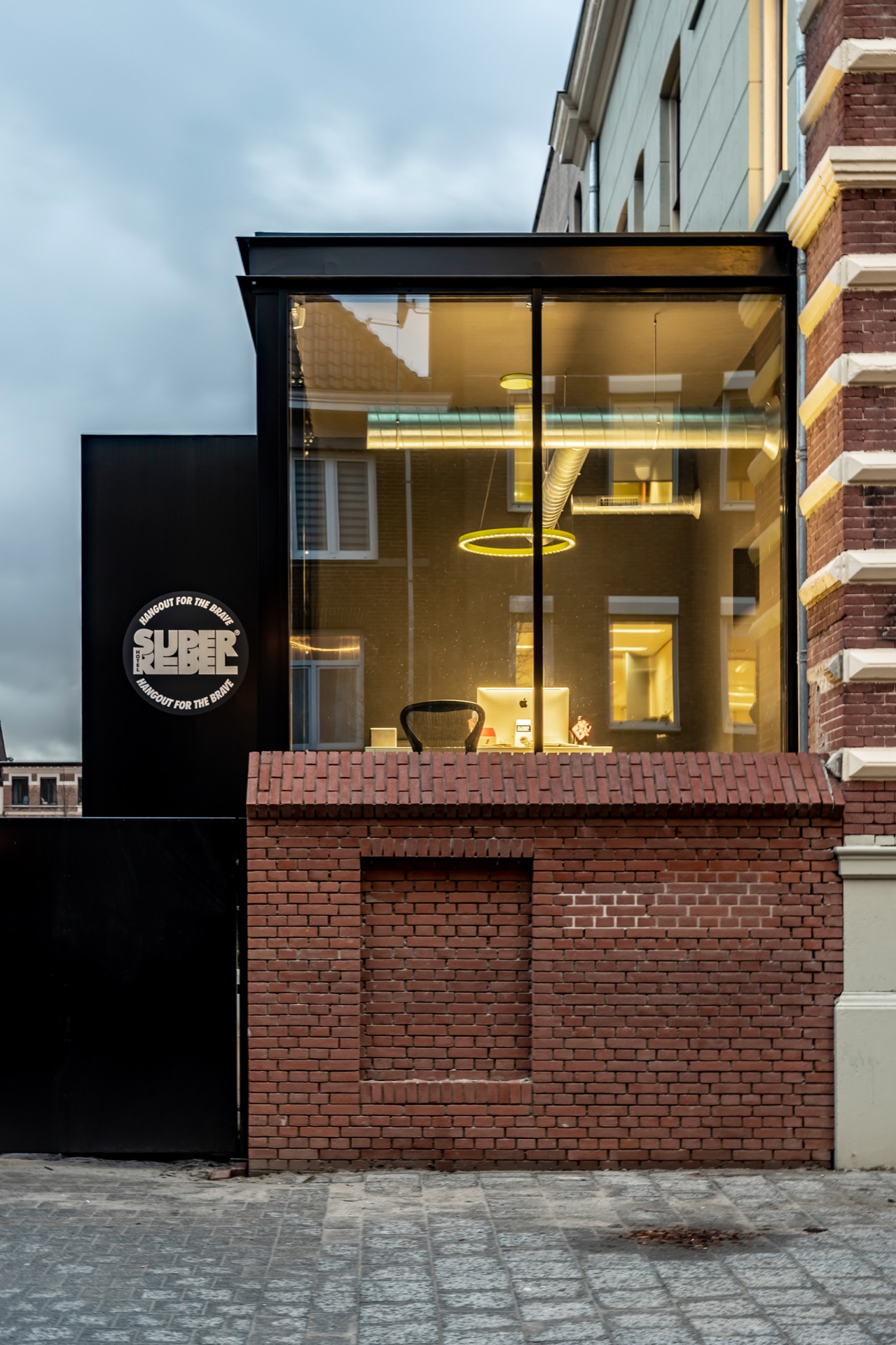 Modern black and glass extension at the rear of Hotel SuperRebel at dusk